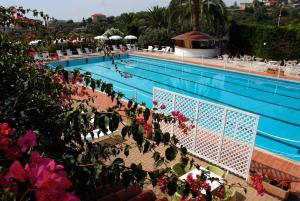 圣雷莫拉孔卡阿祖拉酒店的游泳池前有粉红色的花朵