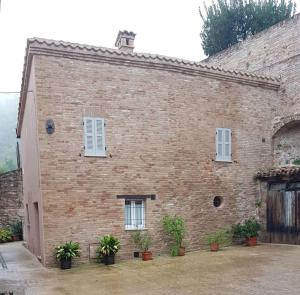 乌尔比诺Casa la Piazzetta Rinascimentale的前面有盆栽植物的砖砌建筑