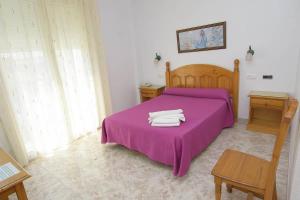 卡沃内拉斯HOTEL DON FELIPE的一间卧室配有一张紫色床和两条毛巾