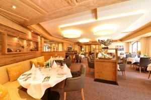 里茨勒恩加戈霍夫酒店的餐厅设有白色的桌椅和木制天花板。