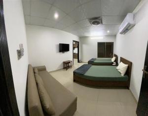 费萨拉巴德• Faizi Furnished Apartments的一间设有两张床和一张沙发的房间