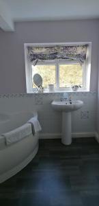 卡莱尔Newby Cross的带浴缸、水槽和窗户的浴室