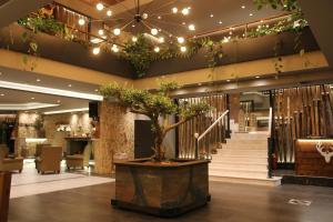 哈尔基斯Hotel Anthidon Estate的大厅,在大楼中间有一棵盆子树