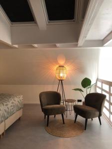 HeerdeB&B Onderderietenkap的卧室配有两把椅子、一盏灯和一张床