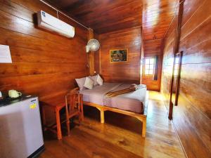 素可泰Perfect Resort Sukhothai & motorbikes for rent & bicycles for rent的木制客房内配有一张床和一张书桌的房间