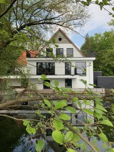 蒂伦豪特Vakantiehuis Ochtendgloren的前面有池塘的白色房子