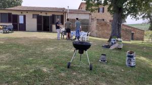 皮恩扎Podere la Miniera的三人站在院子里,带烧烤架