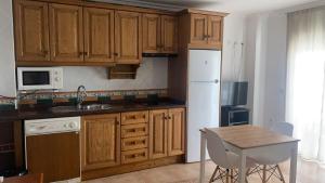 内尔哈巴尔肯德卡拉贝欧公寓酒店的厨房配有木制橱柜、桌子和白色冰箱。