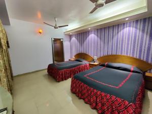 吉大港Asian SR Hotel的一间卧室设有两张床和紫色墙壁