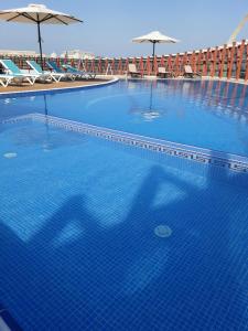 多哈Cielo Hotel Lusail Qatar的一个带椅子和遮阳伞的大型蓝色游泳池