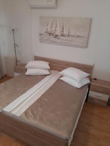亚德里亚Apartments Adria的一张带两个枕头的床和墙上的绘画