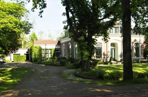 ZuidhornDe oude dokterspraktijk的前面有树木的大白色房子