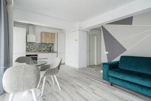 马马亚Bel Air Apartments Mamaia Nord的客厅配有蓝色的沙发、桌子和椅子