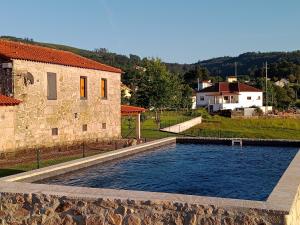 FontouraCasa da Quinta do Cruzeiro的石头建筑前的游泳池
