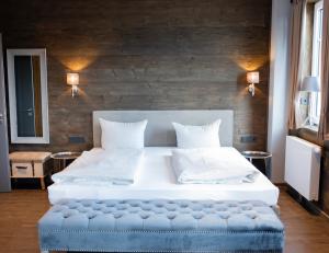 布劳恩拉格StrandBerg's Ursprung: Spa & Kitchen的一间卧室配有一张大床和蓝色的搁脚凳