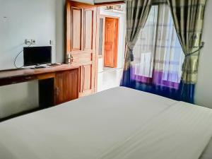 庞岸达兰RedDoorz Syariah near Sunrise Park Pangandaran的一间卧室设有一张床、一台电视和一个窗口。