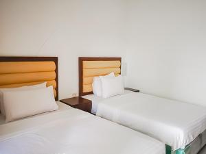 庞岸达兰RedDoorz Syariah near Sunrise Park Pangandaran的两张睡床彼此相邻,位于一个房间里