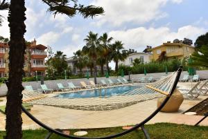 锡德Nora Suit Hotel的度假村内的吊床,配有椅子和游泳池