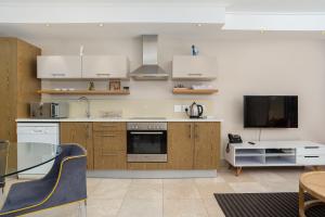 开普敦Canal Quays Apartments的厨房配有白色橱柜、桌子和电视。