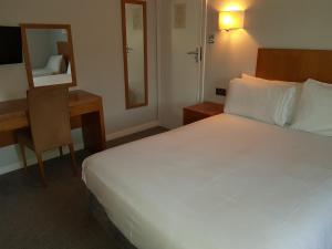 伯明翰Tri-Star Hotel的一间卧室配有一张床、一张书桌和一面镜子