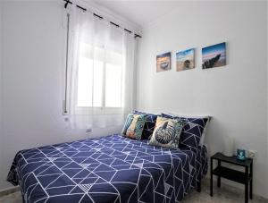 科尼尔-德拉弗龙特拉Conil Centro & Playa, descanso perfecto, Aire Ac y WIFI -SOLO FAMILIAS Y PAREJAS-的一间卧室配有一张带蓝色棉被的床和窗户。