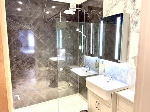 塞米斯湾Gwesty Gadlys Hotel的带淋浴、两个盥洗盆和镜子的浴室
