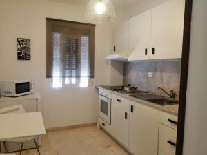 圣费尔南多Room in Lovely cottage house Habitaciones en Chalet en Cadiz San Fernando的厨房配有白色橱柜和水槽
