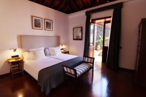 埃尔米瓜Hotel Escuela Rural Casa Los Herrera的卧室配有一张白色大床和一把椅子