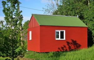 旧皮耶巴尔加自治市Lauku namiņš - Country cottage的田野上带绿色屋顶的红色房子