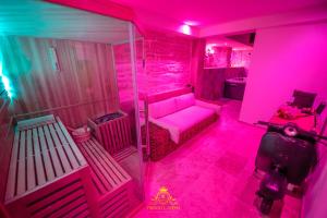阿维尼翁L'EXCELLENCE AVIGNON - Suite LUXE SAUNA, HAMMAM & JACCUZZI的粉红色的客房设有一张沙发和一张桌子