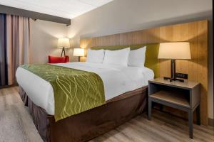 利物浦Comfort Inn & Suites的一间卧室配有一张大床和一张带台灯的桌子