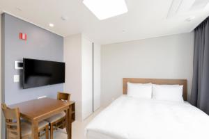 东海市Donghae Oceancity Residence Hotel的一间卧室配有一张床、一张书桌和一台电视。