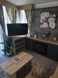 布莱克浦Luxury Latest Model Holiday Home的客厅配有平面电视和桌子。