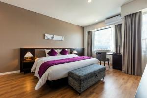 海防Roygent Parks Hai Phong的一间卧室配有一张带紫色枕头的大床