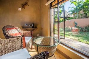 圣卢西亚阿玛祖鲁旅舍的客房设有玻璃桌、椅子和窗户。