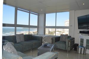 德班Accommodation Front - Classy 4 Sleeper with Ocean Views的带沙发、椅子和窗户的客厅