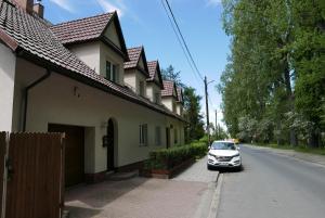 克拉科夫Apartament Parkowy的停在房子旁边的人行道上的汽车