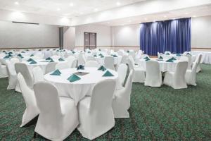 柯克斯维尔柯克斯维尔戴斯酒店的一间会议室,配有白色的桌椅和蓝色的餐巾