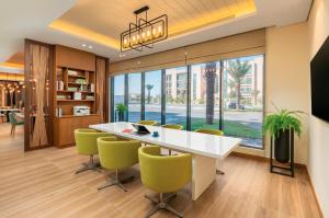 奥朱贝尔Holiday Inn & Suites Al Jubail, an IHG Hotel的一间设有白色桌子和绿色椅子的用餐室