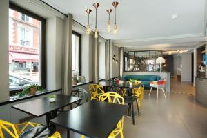 巴黎艾菲尔国会大厦酒店的用餐室配有桌子和黄色椅子