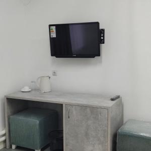 AksaySulo Aksai Hotel的挂在墙上的电视,配有书桌