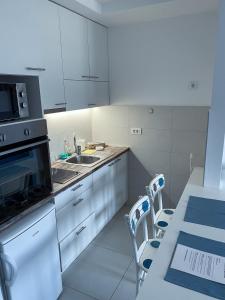 Novi BeogradApartment Azzurro lux的厨房配有白色橱柜、水槽和桌子
