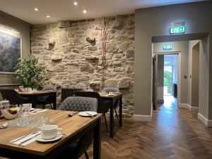 爱丁堡Ben Cruachan Guest House的一间带桌椅和石墙的餐厅