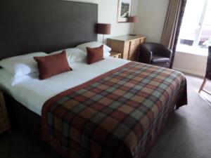阿维莫尔Macdonald Spey Valley Resort的酒店客房带一张大床和一把椅子