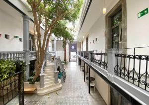 墨西哥城Hotel MX condesa的走廊上有树和楼梯的建筑