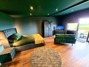 CarrYaseva Lodge, Stylish Country Retreat for 2, Hot Tub, Exceptional Views!的一间卧室配有一张床、一张沙发和一台电视