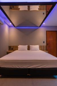 普雷图河畔圣若泽Drops Motel São José do Rio Preto的卧室配有一张白色大床和蓝色的灯光