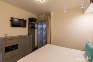 瓦哈卡市Marialicia Suites, Hotel Boutique的卧室配有一张床,墙上配有电视。