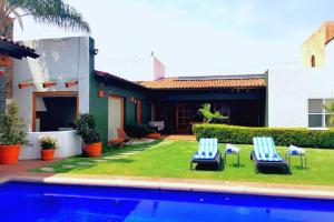 库埃纳瓦卡Casa Luna con alberca privada的一个带两把椅子的庭院和一个游泳池