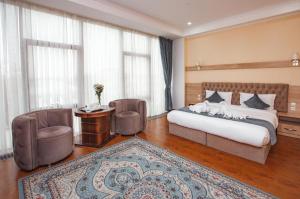 奇姆肯特Park Hotel al Bustan的一间卧室配有一张床、两把椅子和一张桌子
